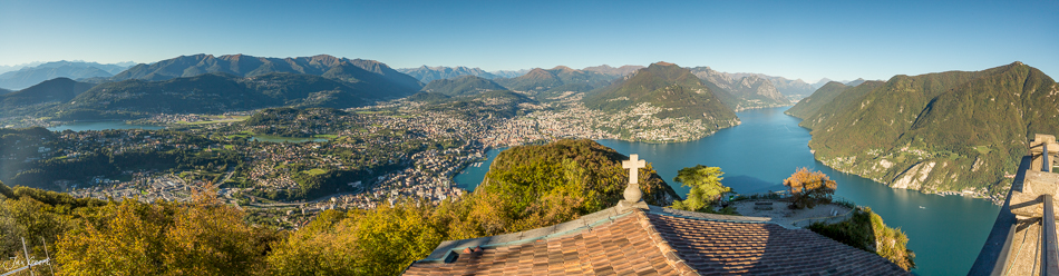 Panoramablick auf Lugano mit Kreuz, See und Bergen bei Sonnenschein – Tessin Schweiz Jan Geerk Fotograf Basel