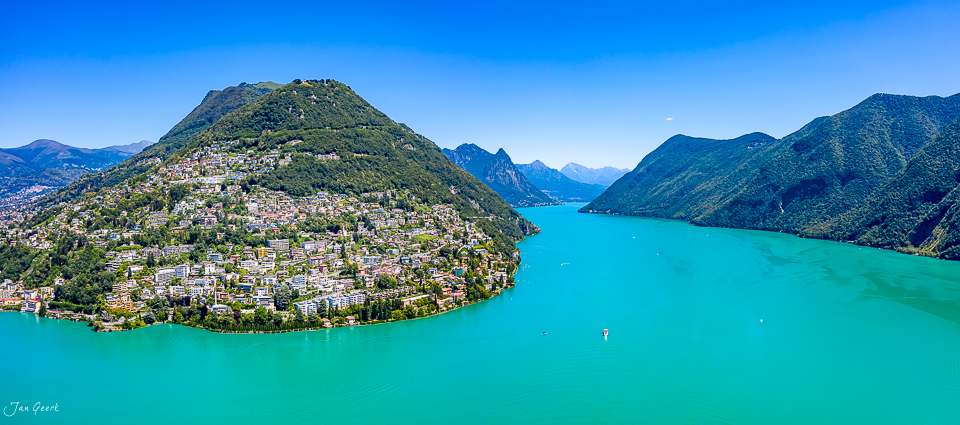 Luftaufnahme Lugano mit türkisfarbenem See, grünen Bergen und Sommerlicht – Tessin Schweiz Jan Geerk Fotograf Basel