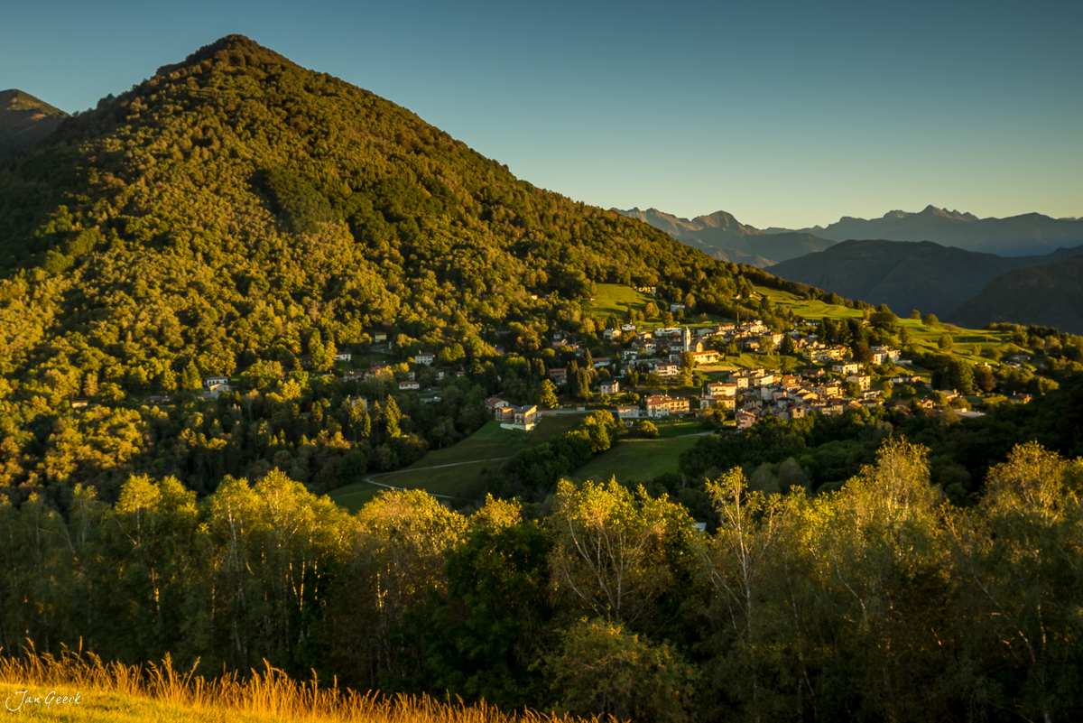 Herbstliche Berglandschaft Malcantone mit buntem Wald und Dorf im Tal Tessin Schweiz – Jan Geerk Fotograf Basel