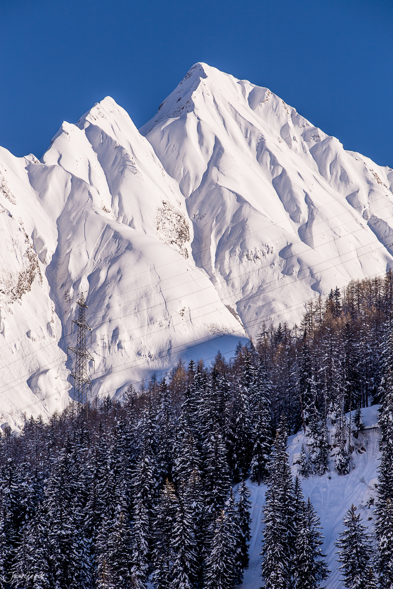 Schneebedeckter Berg über Lärchenwald im Winter, Bedretto Tessin Schweiz – Jan Geerk Fotograf Basel