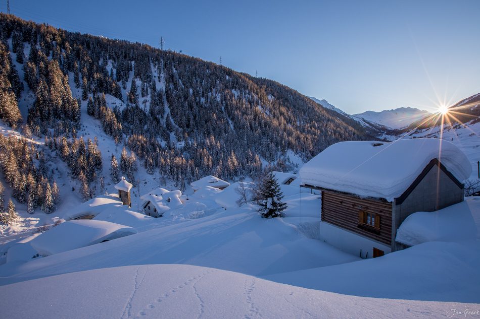 Verschneite Berghütte in Bedretto mit schneebedeckten Lärchenwäldern bei Sonnenaufgang, Tessin Schweiz – Jan Geerk Fotograf Basel