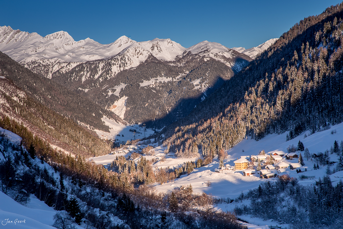 Verschneites Bergdorf Bedretto im Tessin mit schneebedeckten Alpen, Wintermorgen in der Schweiz – Jan Geerk Fotograf Basel
