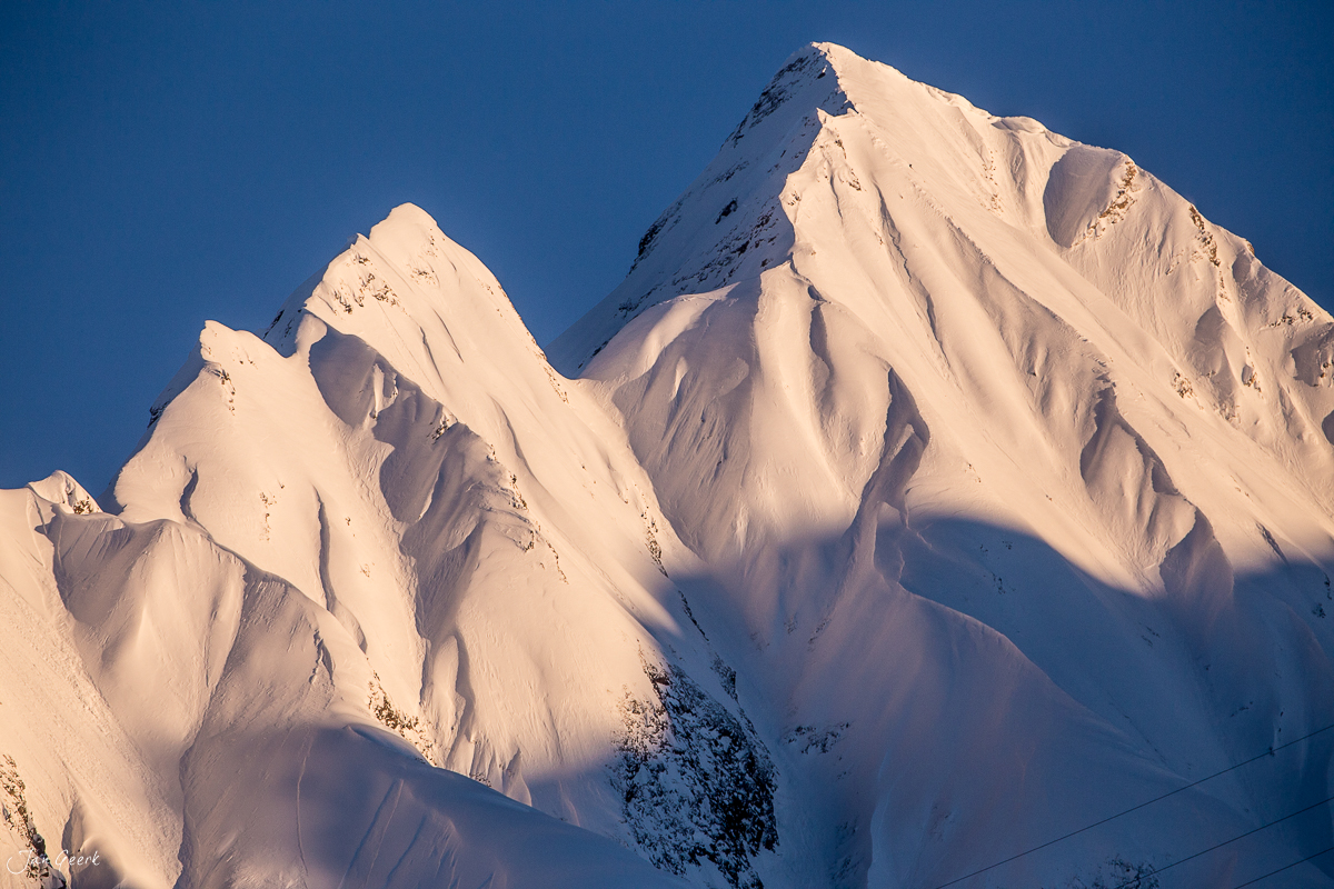 Schneebedeckte Berggipfel im Bedretto bei Airolo mit klarem Himmel im Winterlicht, Tessin Schweiz – Jan Geerk Fotograf Basel