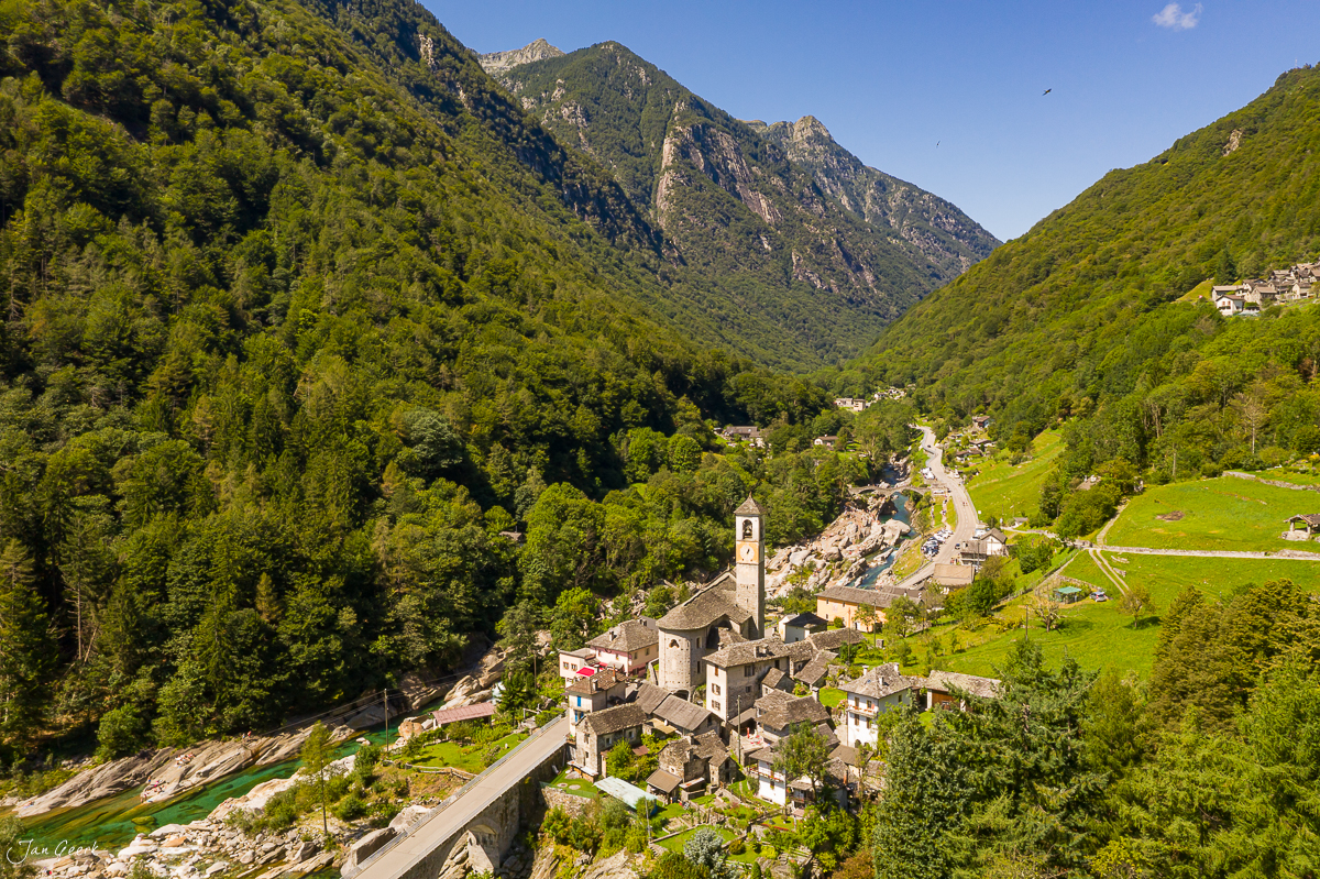 Luftaufnahme des Dorfes Tessin mit Kirche, grünen Bergen und Bergwald in Südschweiz – Jan Geerk Fotograf Basel