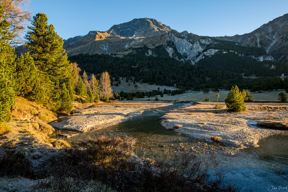 Flusslandschaft mit Lärchen im Herbst, Tessin, golden beleuchtete Berge, Schweiz – Jan Geerk Fotograf Basel