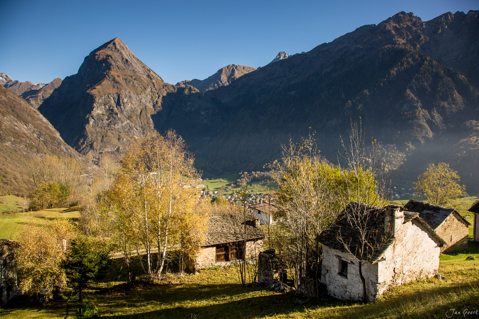 Alte Steinhäuser in Herbststimmung vor imposanten Bergen im Tessin Schweiz – Jan Geerk Fotograf Basel