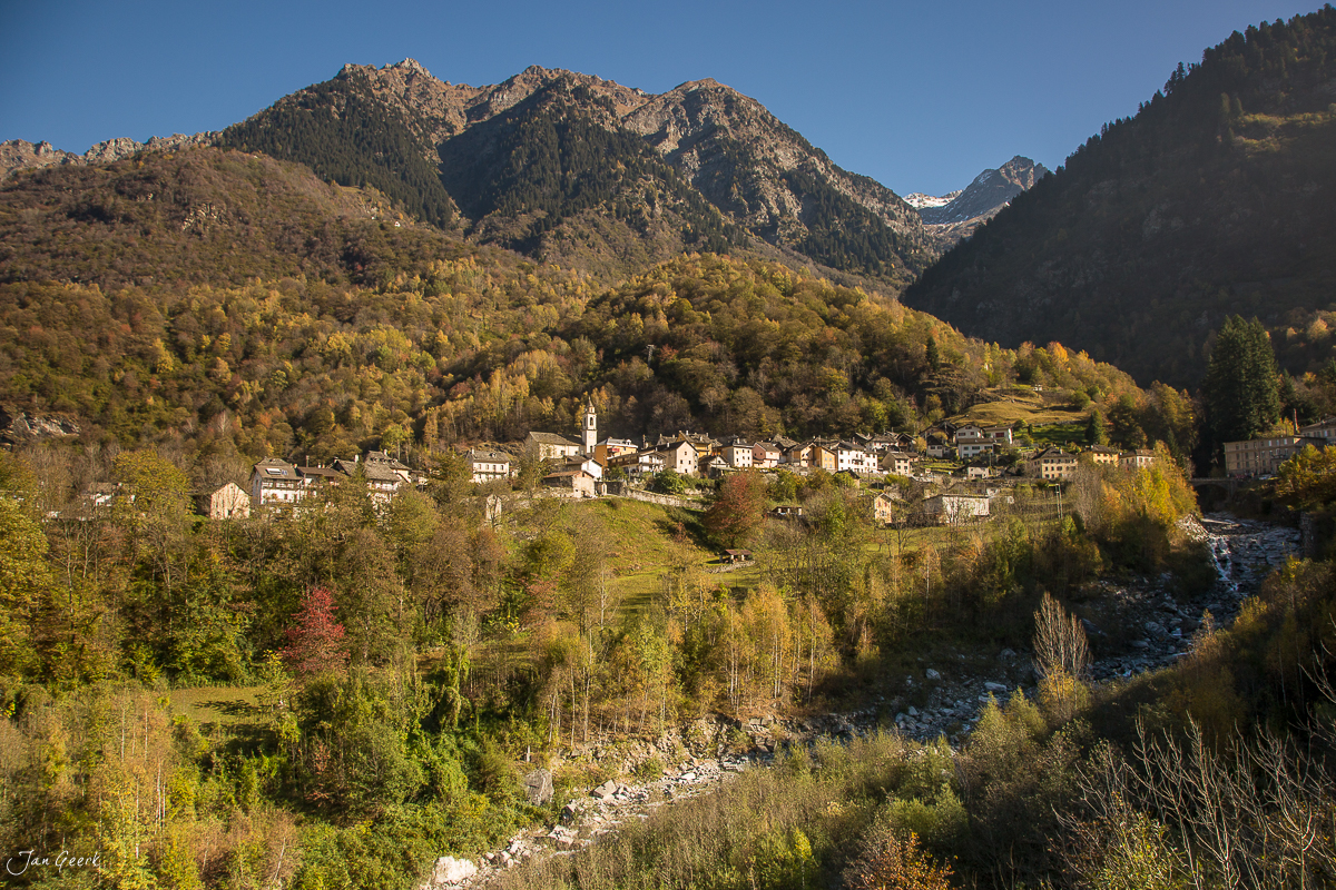 Herbstliches Bergdorf mit Kirchturm in Tessin, von Wald und Bergen umgeben – Jan Geerk Fotograf Basel