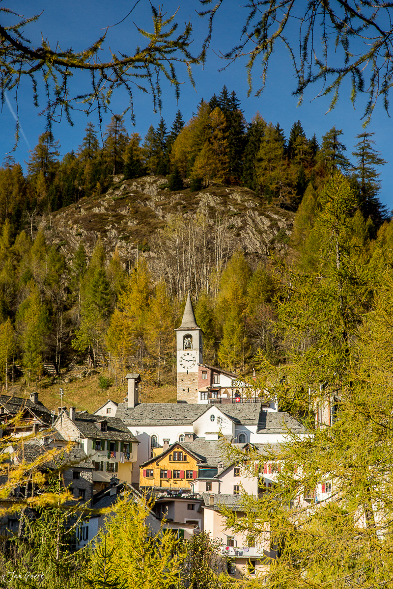Herbstliches Dorf mit Kirche in den Tessiner Alpen, Lärchenwälder golden gefärbt, Schweiz – Jan Geerk Fotograf Basel