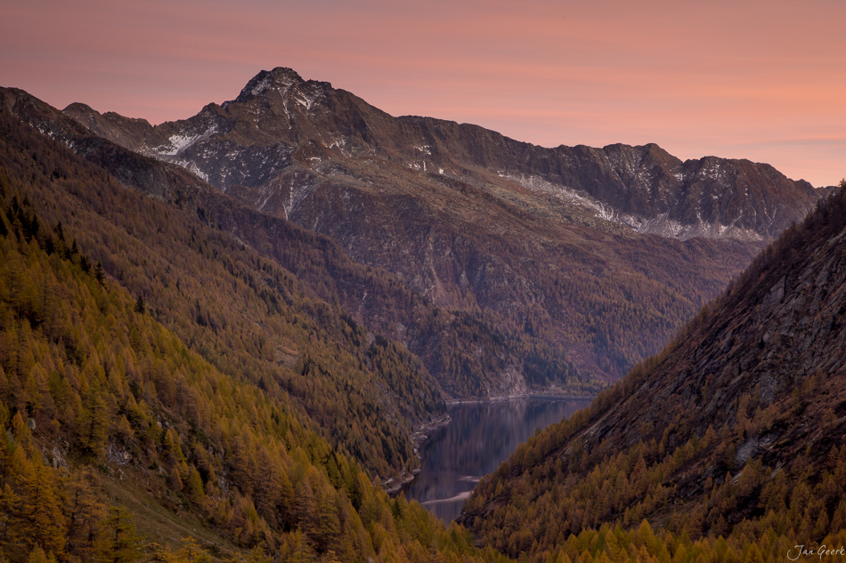 Herbstliche Bergsee-Landschaft im Tessin mit schneebedeckten Gipfeln, goldenen Lärchen und spiegelndem Wasser – Schweiz, Jan Geerk Fotograf Basel