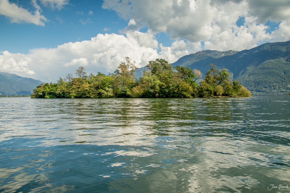 Waldinsel im Lago Maggiore bei Ascona mit Seeufer, Bergpanorama und Sommerhimmel, Tessin Schweiz – Jan Geerk Fotograf Basel