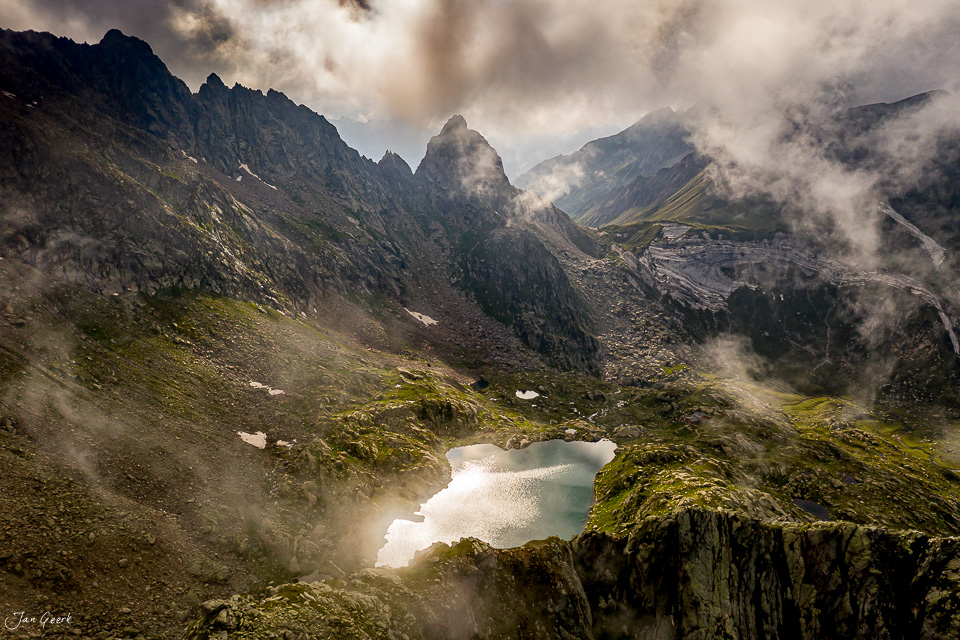 Bergsee mit Drohne fotografiert in den Alpen des Tessins, umgeben von Nebel und grünen Wiesen – Jan Geerk Fotograf Basel Schweiz