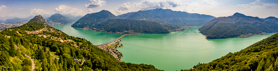 Luftaufnahme des türkisgrünen Sees mit Bergen und grünen Wäldern, Tessin, sonniger Sommertag, Südschweiz – Jan Geerk Fotograf Basel