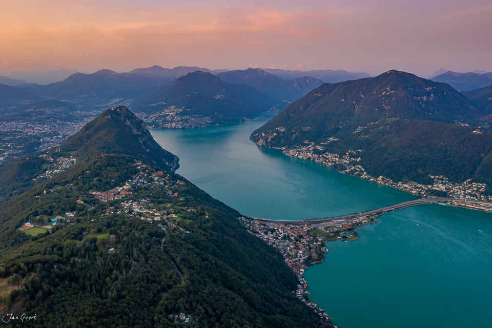 Luftaufnahme Tessin mit türkisblauem See, umgeben von Bergen und Siedlungen bei Sonnenuntergang, Südschweiz – Jan Geerk Fotograf Basel