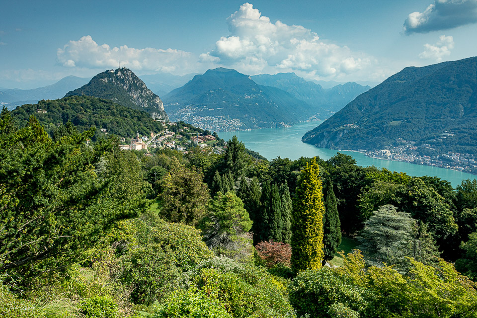 Alpenseepanorama mit bewaldeten Bergen und türkisem Seewasser im Tessin Schweiz – Jan Geerk Fotograf Basel