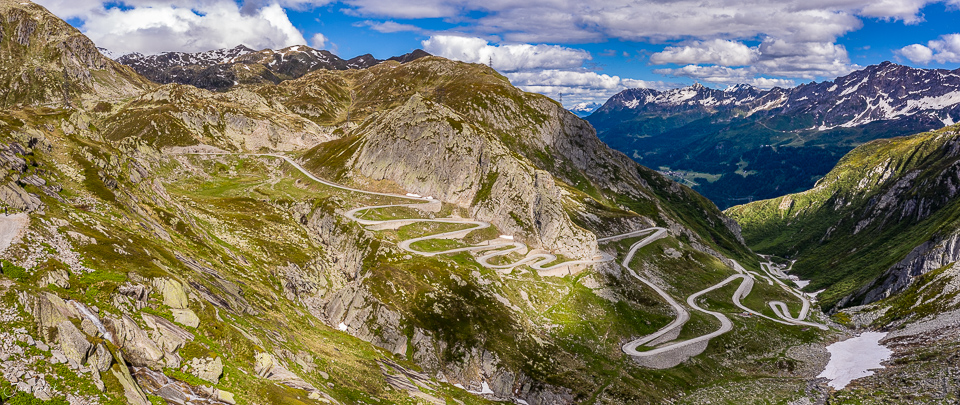 Luftaufnahme der Tremola Passstrasse am Gotthard mit Serpentinen, grüne Berglandschaft, Sommerlicht, Tessin, Schweiz – Jan Geerk Fotograf Basel
