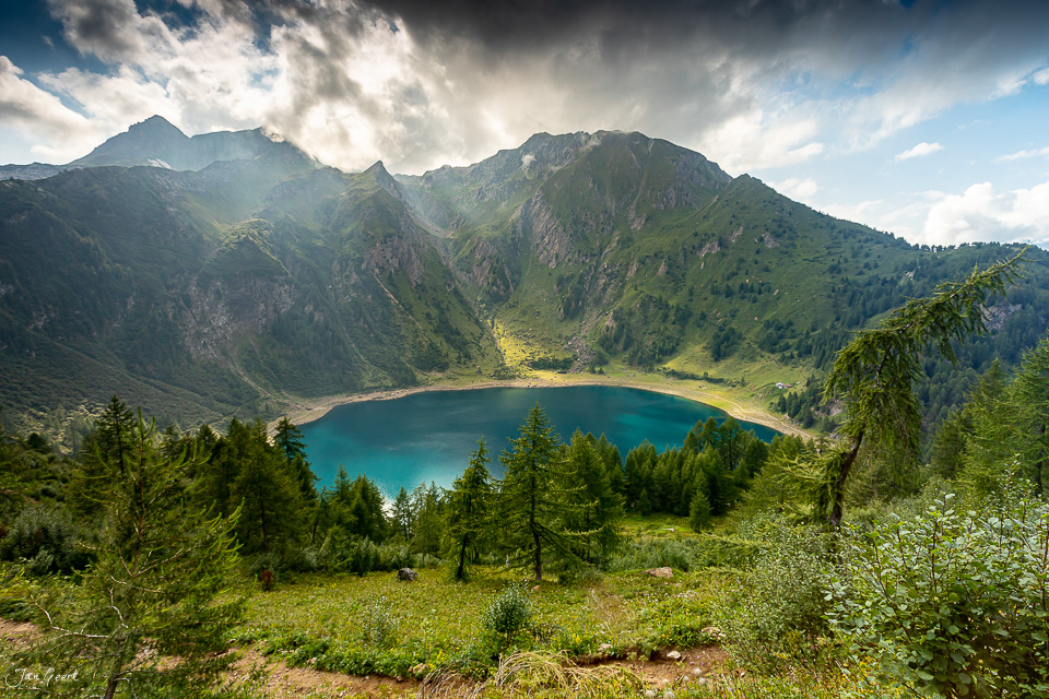 Alpiner See mit türkisblauem Wasser, umgeben von grünen Bergen und Nadelwäldern im Tessin, Sommerstimmung, Südschweiz – Jan Geerk Fotograf Basel