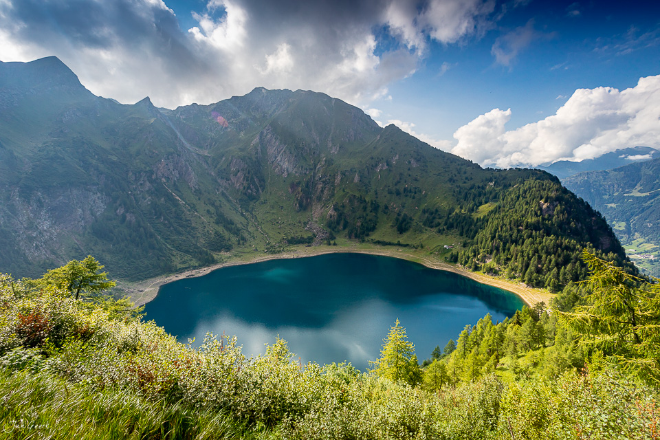 Alpiner See mit türkisblauem Wasser, umgeben von Bergwald und Felswänden, Tessin Sommerlicht Schweiz – Jan Geerk Fotograf Basel