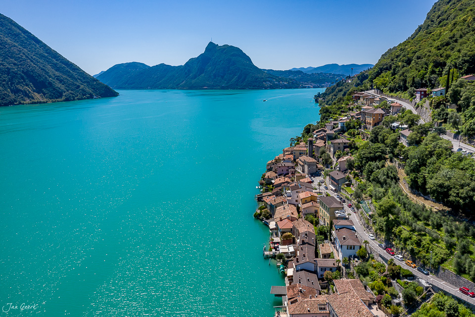 Luftaufnahme Gandria am Lugano mit türkisblauem Wasser, Berge und Dorf im Tessin Schweiz – Jan Geerk Fotograf Basel