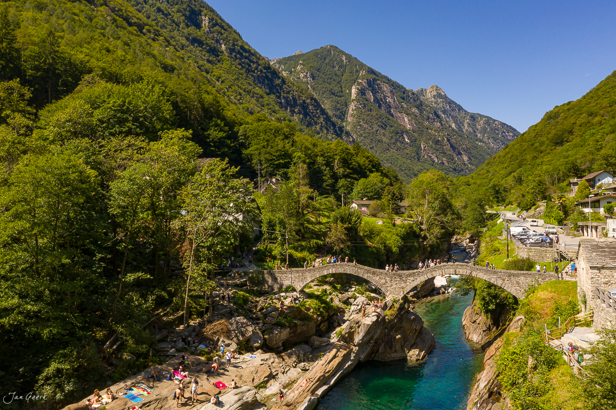 Steinbrücke über türkisgrünem Fluss in Lavertezzo mit bewaldeten Bergen, sonniger Sommertag, Tessin Schweiz – Jan Geerk Fotograf Basel