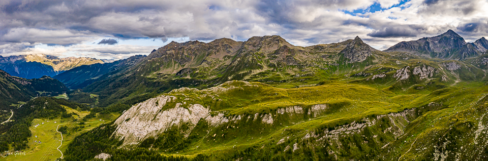 Alpenpanorama Tessin mit grünen Wiesen, Berggipfeln und dramatischem Himmel, Schweiz – Jan Geerk Fotograf Basel