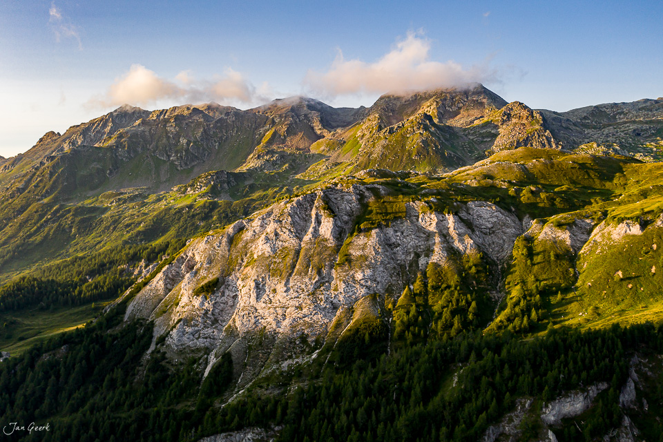 Luftaufnahme Lukmanierpass mit steilen Felsklippen, grünen Alpweiden und Bergpanorama in sommerlicher Lichtstimmung, Südschweiz – Jan Geerk Fotograf Basel