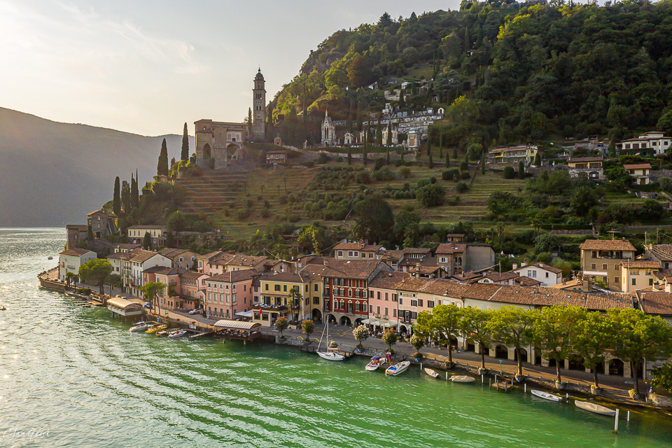Malerisches Dorf am Seeufer mit Kirche und grünen Bergen im Tessin, Schweiz – Jan Geerk Fotograf Basel