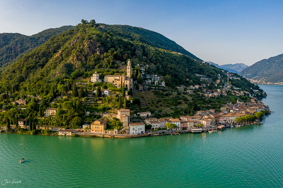 Luftaufnahme Morcote mit Kirche, grünem See und bewaldeten Bergen im Tessin, Schweiz – Jan Geerk Fotograf Basel