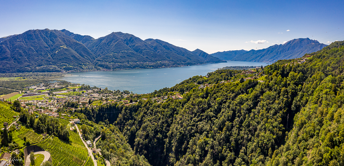 Luftaufnahme des Sees Tessin mit grünen Wäldern, Bergen und Dörfern an sonnigem Tag – Schweiz, Jan Geerk Fotograf Basel