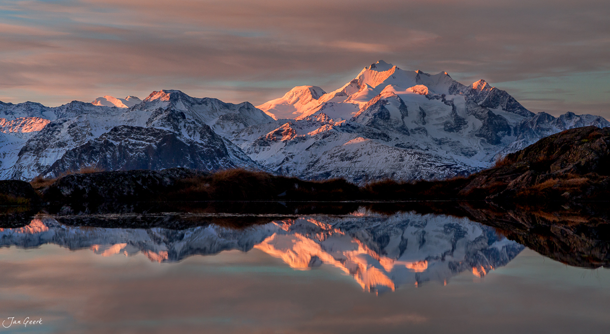 Schneebedeckte Berge spiegeln sich in ruhigem See im Aletschgebiet während goldener Herbststimmung, Wallis Schweiz – Jan Geerk Fotograf Basel