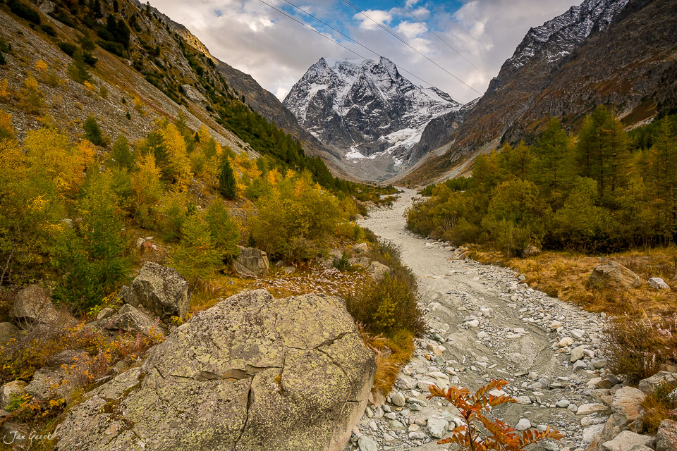 Alpental mit schneebedecktem Berg, Gebirgsstrom und Lärchenwald im Herbst Wallis Schweiz – Jan Geerk Fotograf Basel