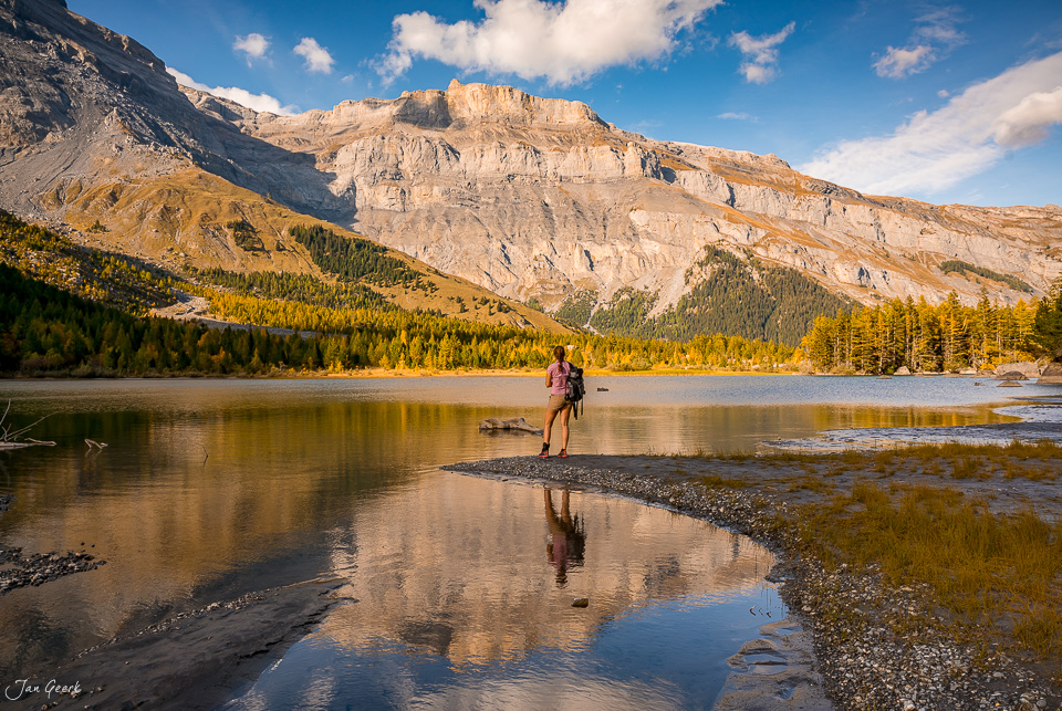 Frau am Seeufer des Lac de Derborence im Herbst mit Lärchenwäldern und Felswand Wallis Schweiz Jan Geerk Fotograf Basel