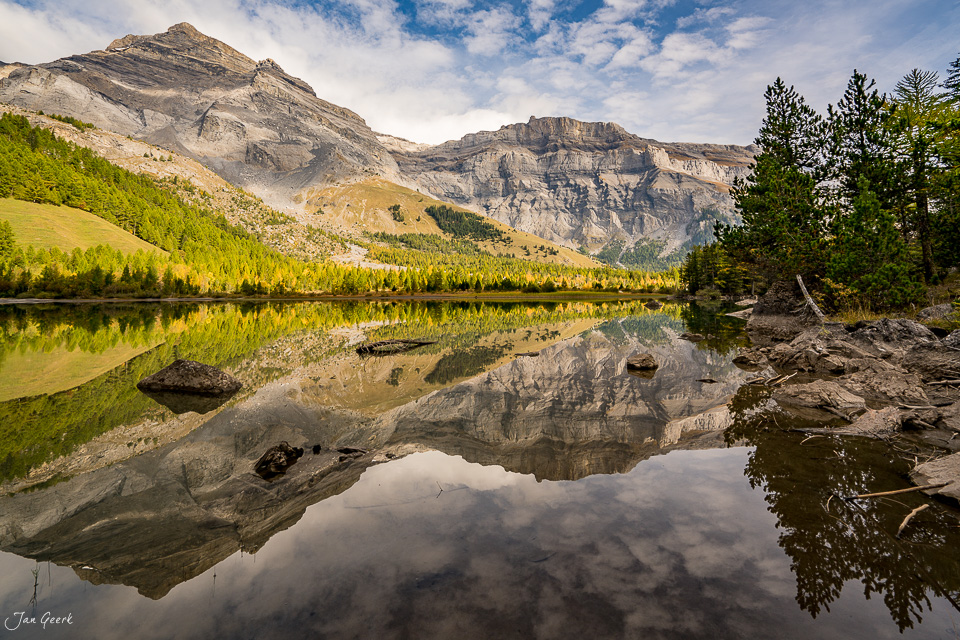Spiegelnder Bergsee mit herbstlichen Lärchen und Bergketten bei Derborence Wallis Schweiz – Jan Geerk Fotograf Basel