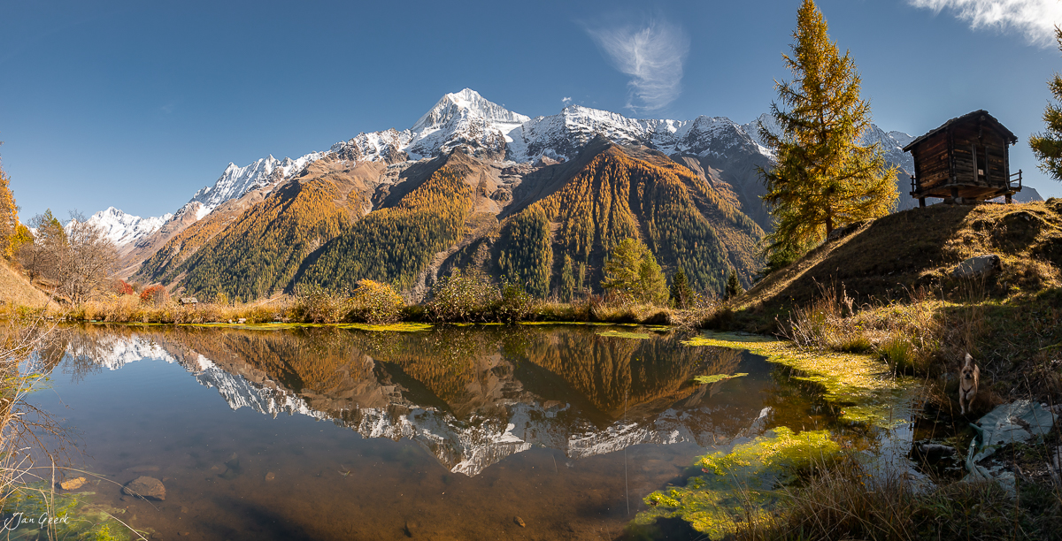 Spiegelnde Wasserfläche mit schneebedeckten Bergen und goldenen Lärchen im Herbst im Lötschental Wallis Schweiz Jan Geerk Fotograf Basel