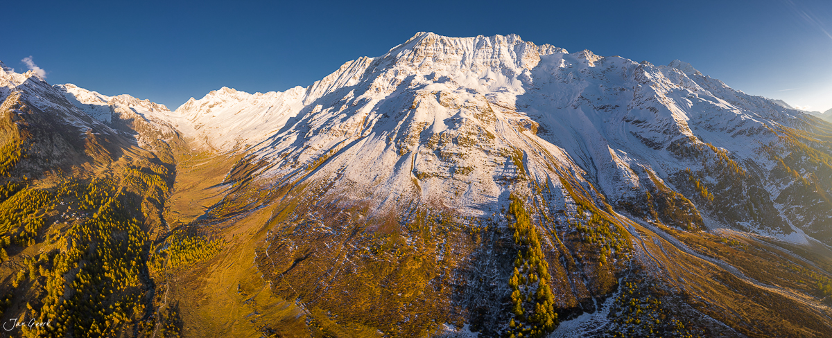 Schneebedeckter Berg mit Lärchenwäldern im Herbst Lötschental Wallis Schweiz – Jan Geerk Fotograf Basel