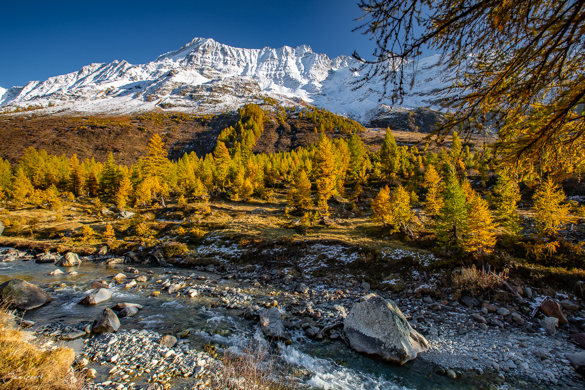 Herbstliche Lärchen und Bergbach im Lötschental mit schneebedecktem Matterhorn, Wallis, Schweiz – Jan Geerk Fotograf Basel