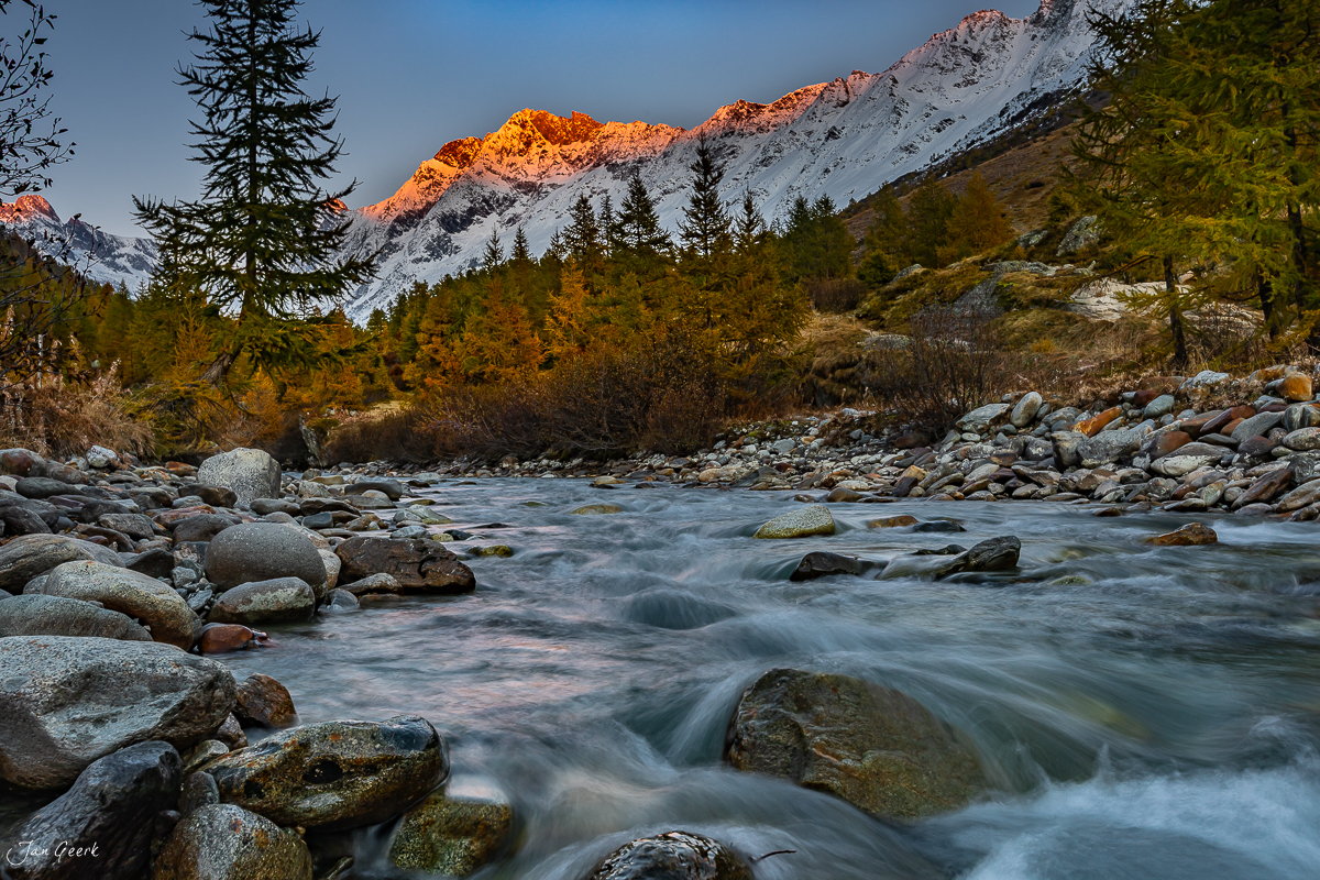 Herbstliche Gebirgslandschaft im Lötschental mit schneebedeckten Gipfeln, klaren Gebirgsbächen zwischen Lärchenwald und Felsen, Wallis Schweiz – Jan Geerk Fotograf Basel