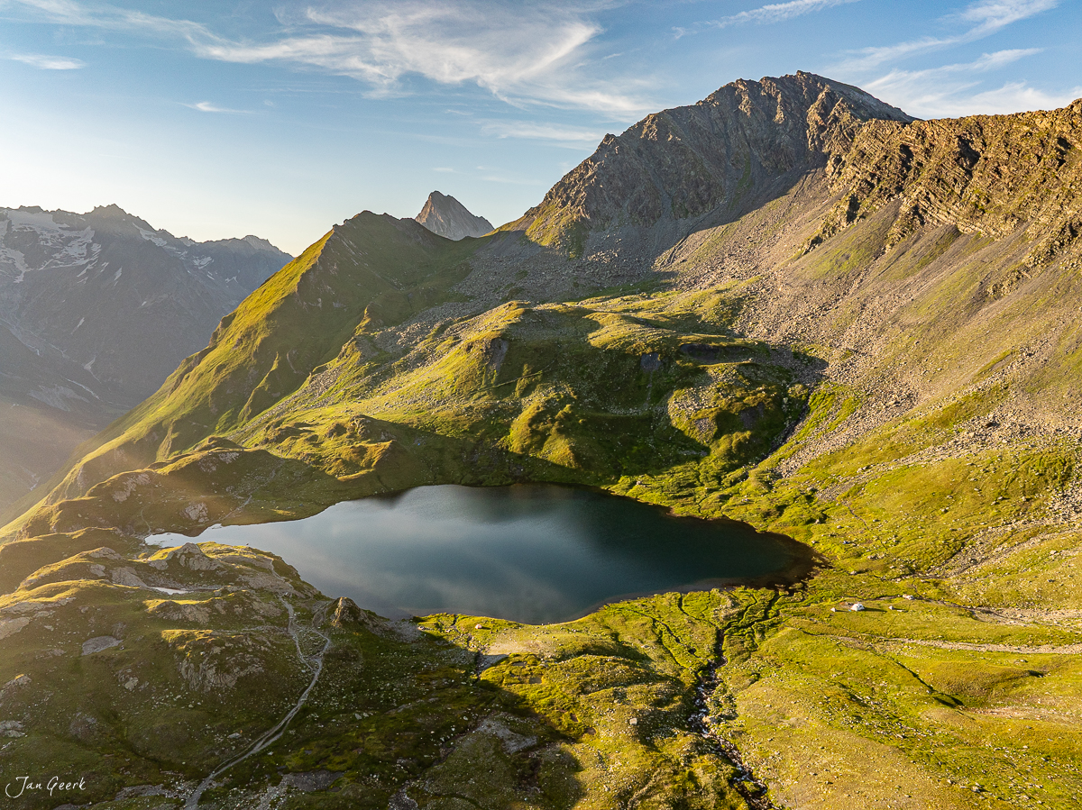 Alpiner Bergsee in den Lacs de Fenetre mit grünen Wiesen und Bergspitzen, Sommerlicht im Wallis Schweiz – Jan Geerk Fotograf Basel