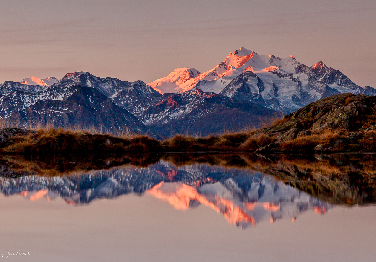 Schneebedeckte Alpengipfel spiegeln sich in Bergsee beim Alpenglühen Riederalp Bettmeralp Wallis Schweiz