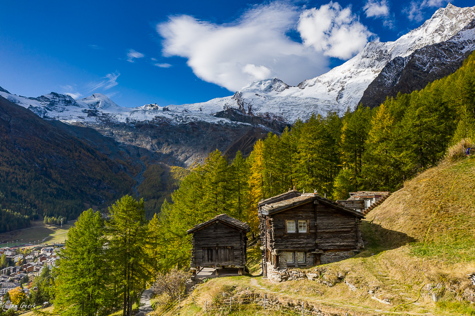 Alte Holzhütten in der Aletschregion mit schneebedeckten Gletschern und Lärchenbäumen im Herbst, Wallis Schweiz – Jan Geerk Fotograf Basel