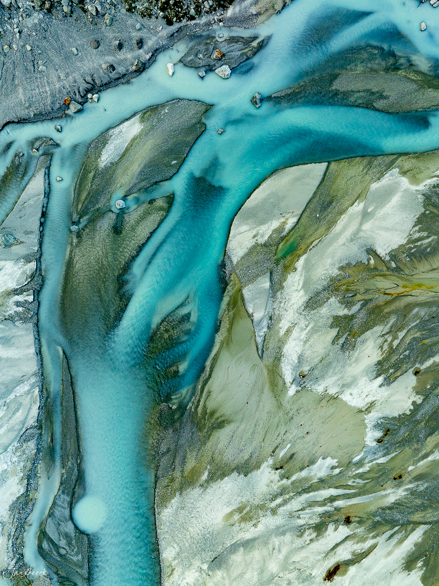 Türkisblauer Gletscherfluss im Wallis umfließt grüne Berghänge, Alpensommer, Schweiz – Jan Geerk Fotograf Basel
