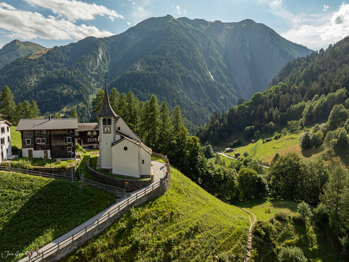 Dorfkirche mit Glockenturm im Binntal, grüne Berglandschaft mit Nadelwäldern, Sommerliche Bergkulisse Wallis Schweiz – Jan Geerk Fotograf Basel