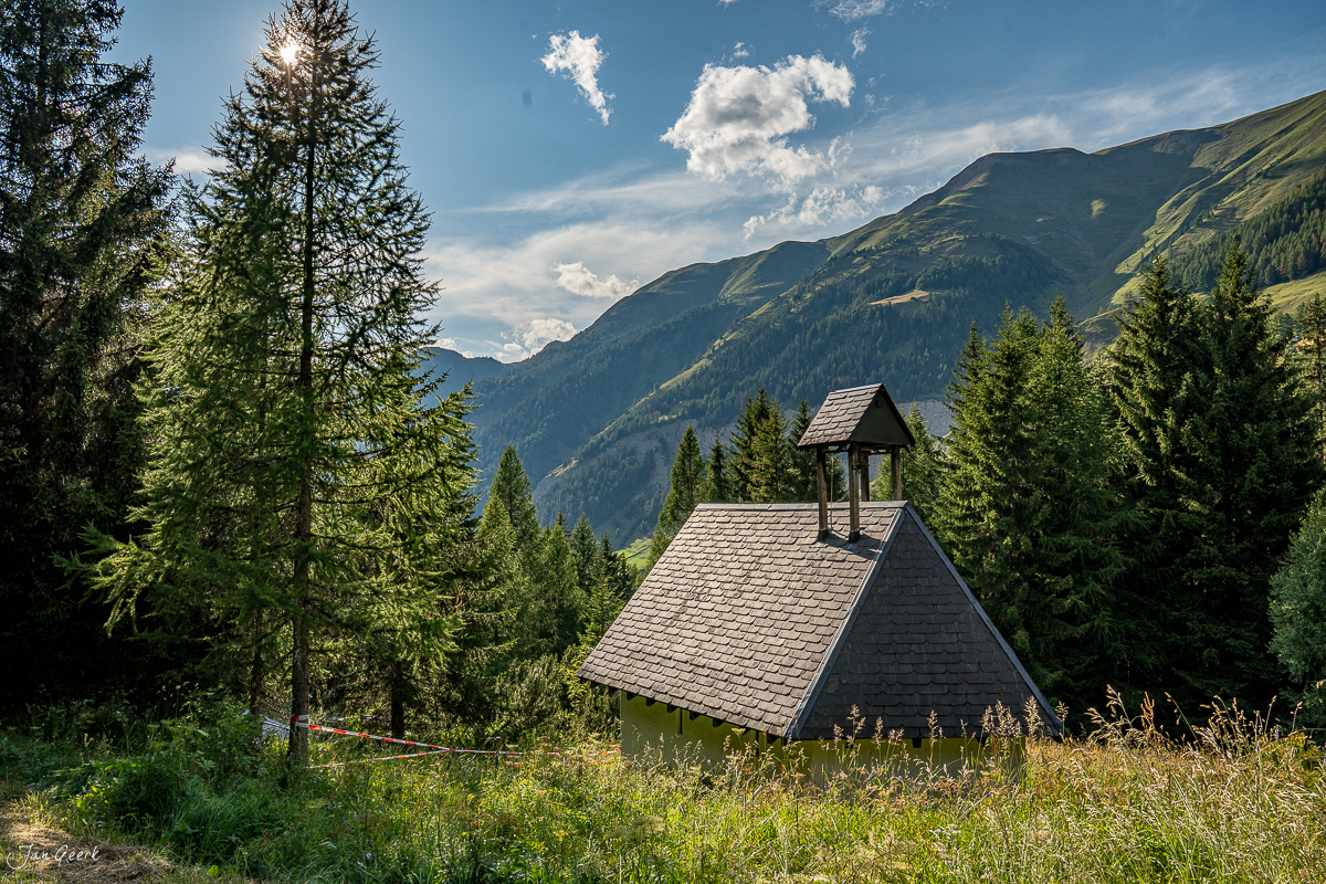 Kleine Kapelle im Bergtal Goms mit Lärchenwald und Alpengipfeln, Sommerlicht, Wallis Schweiz – Jan Geerk Fotograf Basel