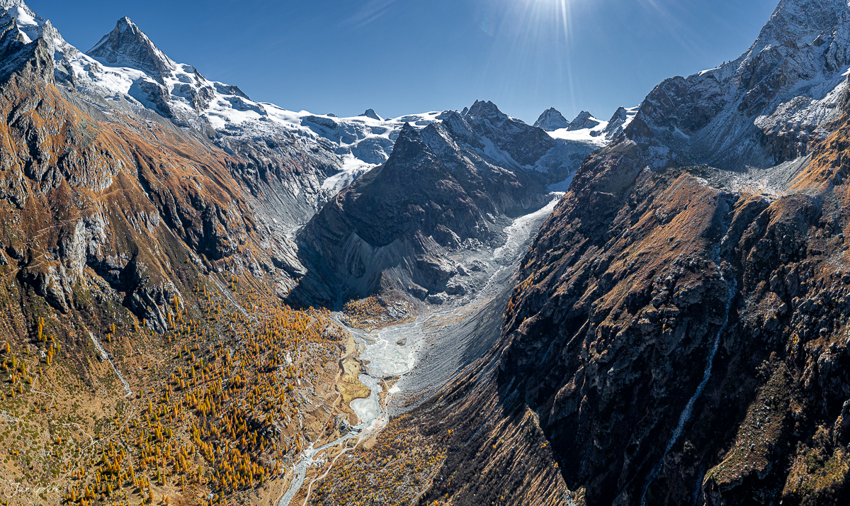Gletscherlandschaft Val d'Hérens mit schneebedeckten Gipfeln, Herbstwald und Gletscherzunge in der Sonne Wallis Schweiz Jan Geerk Fotograf Basel