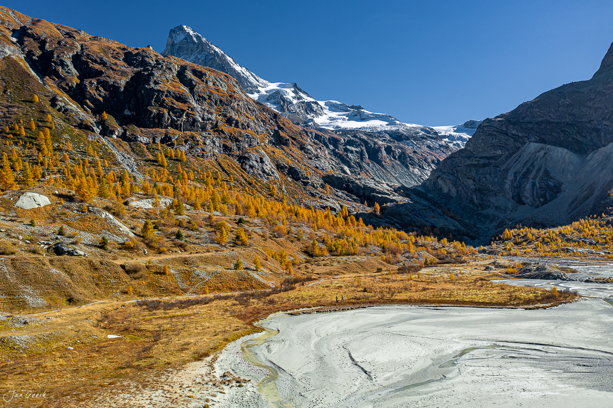 Herbstliche Lärchenwälder im Val d'Hérens mit schneebedeckten Gipfeln, Gebirgsfluss und goldenes Licht – Schweiz – Jan Geerk Fotograf Basel