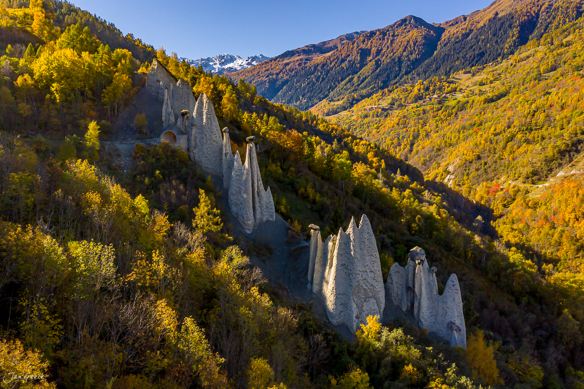 Erdpyramiden von Euseigne im Herbst mit goldgelbem Lärchwald und schneebedeckten Bergen, Wallis, Schweiz – Jan Geerk Fotograf Basel