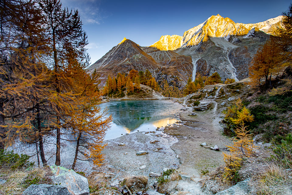 Alpensee mit goldenen Lärchen, Berge im Herbstlicht, Val d'Hérens Wallis Schweiz – Jan Geerk Fotograf Basel