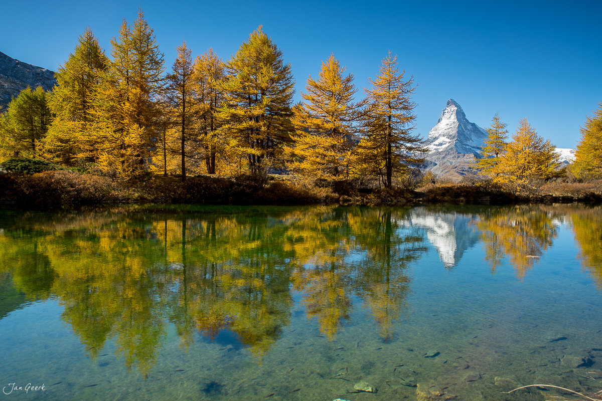 Herbstliche Lärchen spiegeln sich im Riffelsee mit dem Matterhorn im Hintergrund, Zermatt Wallis Schweiz – Jan Geerk Fotograf Basel