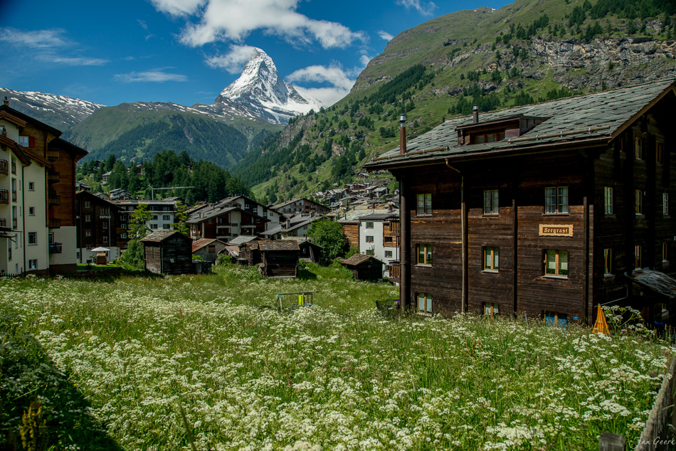 Blühendes Tal mit traditionellen Holzhäusern, Matterhorn im Hintergrund, Sommertag in Zermatt Wallis Schweiz – Jan Geerk Fotograf Basel