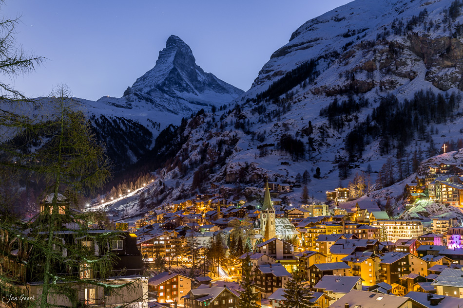 Zermatt im Winter bei Dämmerung mit schneebedecktem Matterhorn und beleuchteten Häusern, Wallis Schweiz – Jan Geerk Fotograf Basel