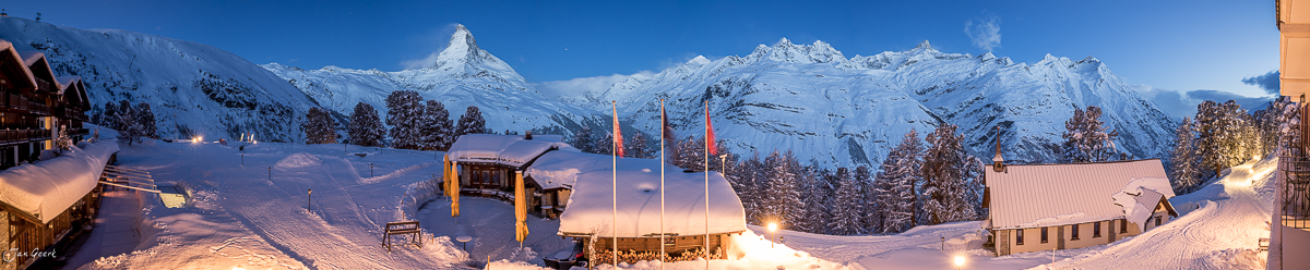 Verschneite Berglandschaft mit beleuchteten Häusern und Matterhorn im Hintergrund bei Riffelalp, Wallis, Schweiz – Jan Geerk Fotograf Basel